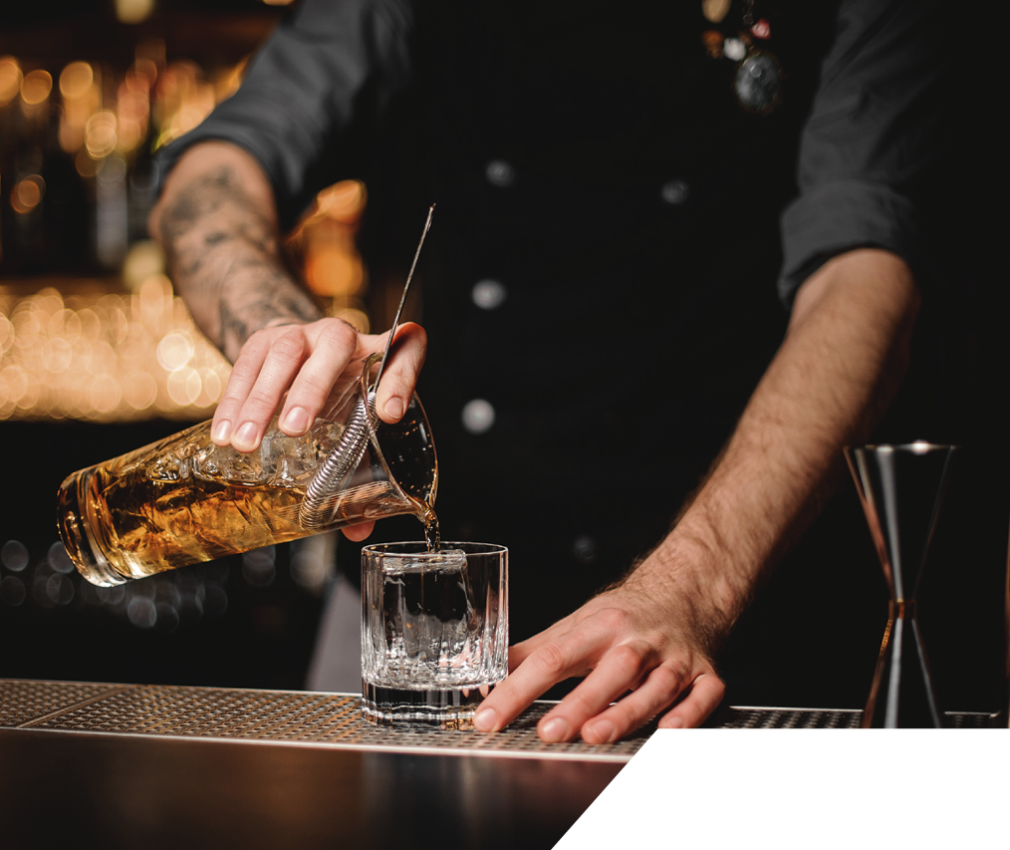 Tower Garden: in der Bar genießen Sie eine Vielfalt an Getränken, alkoholisch und frei von Alkohol Der Barkeeper des Tower Gardens schenkt ein gemixtes Getränk in ein Glas, welches er zuvor mit dem Rühstab professionell abgemischt hat.